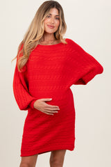 woman wearing a red cable knit maternity dress and holding her baby bump