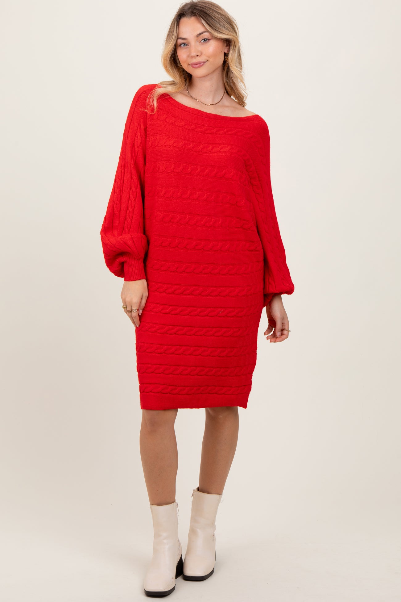 woman wearing a red cable knit sweater dress with long sleeves and a loose fit, styled with ankle boots