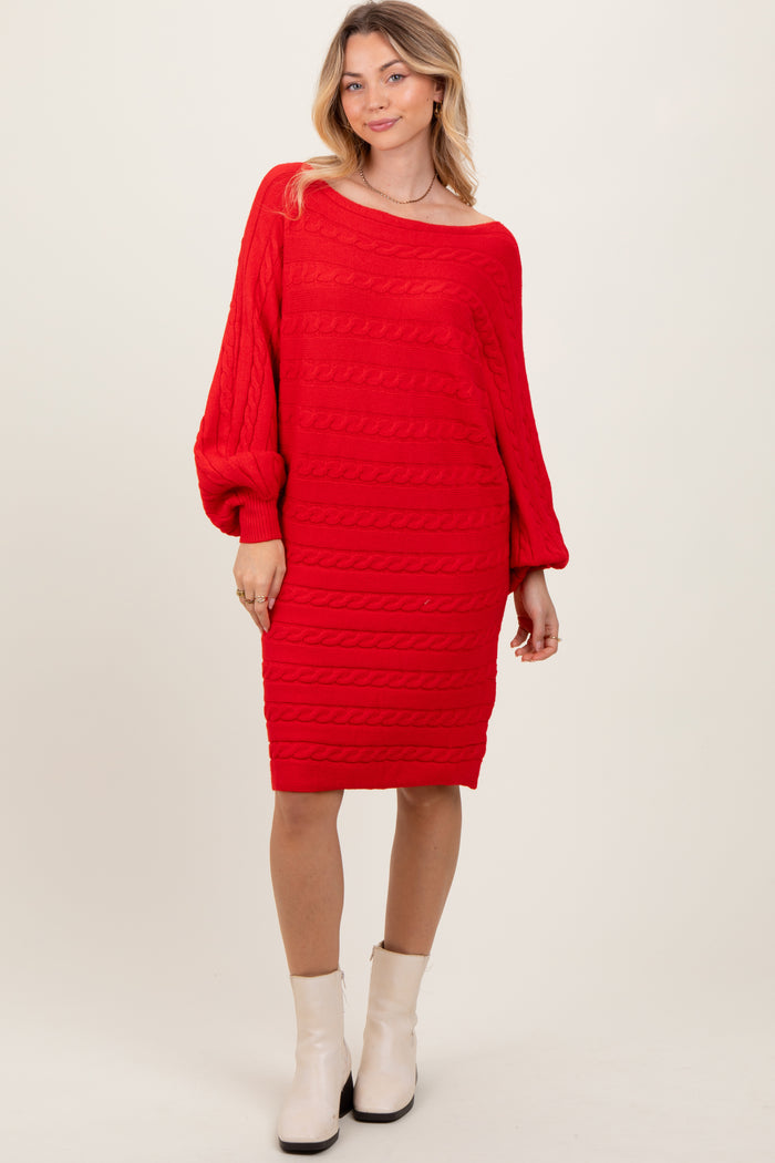 woman wearing a red cable knit sweater dress with long sleeves and a loose fit, styled with ankle boots