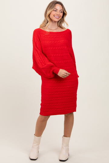 woman wearing a bright red cable knit sweater dress with long sleeves and a relaxed fit, paired with white ankle boots