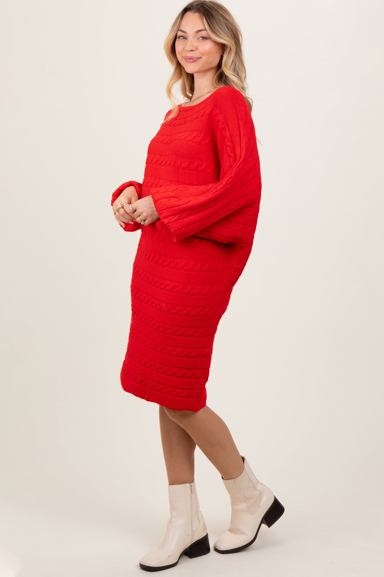 woman wearing a vibrant red cable knit sweater dress with long sleeves and heeled ankle boots