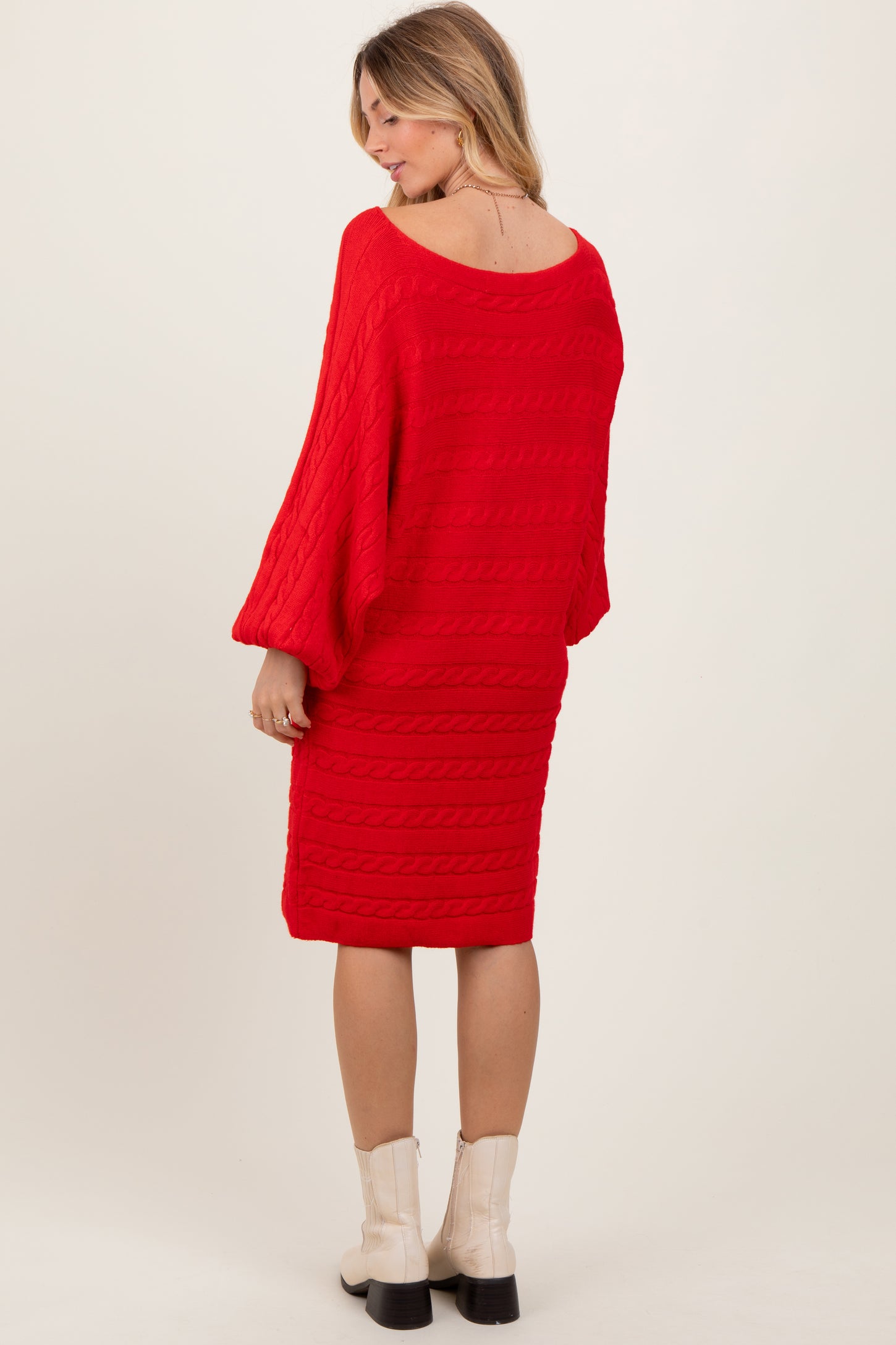 woman wearing a red cable knit sweater dress with balloon sleeves and a fitted hem, viewed from the back