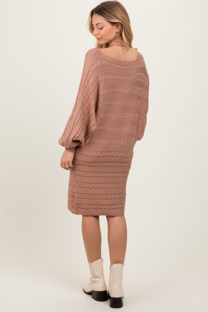 woman wearing a light brown cable knit sweater dress with long sleeves and a relaxed fit