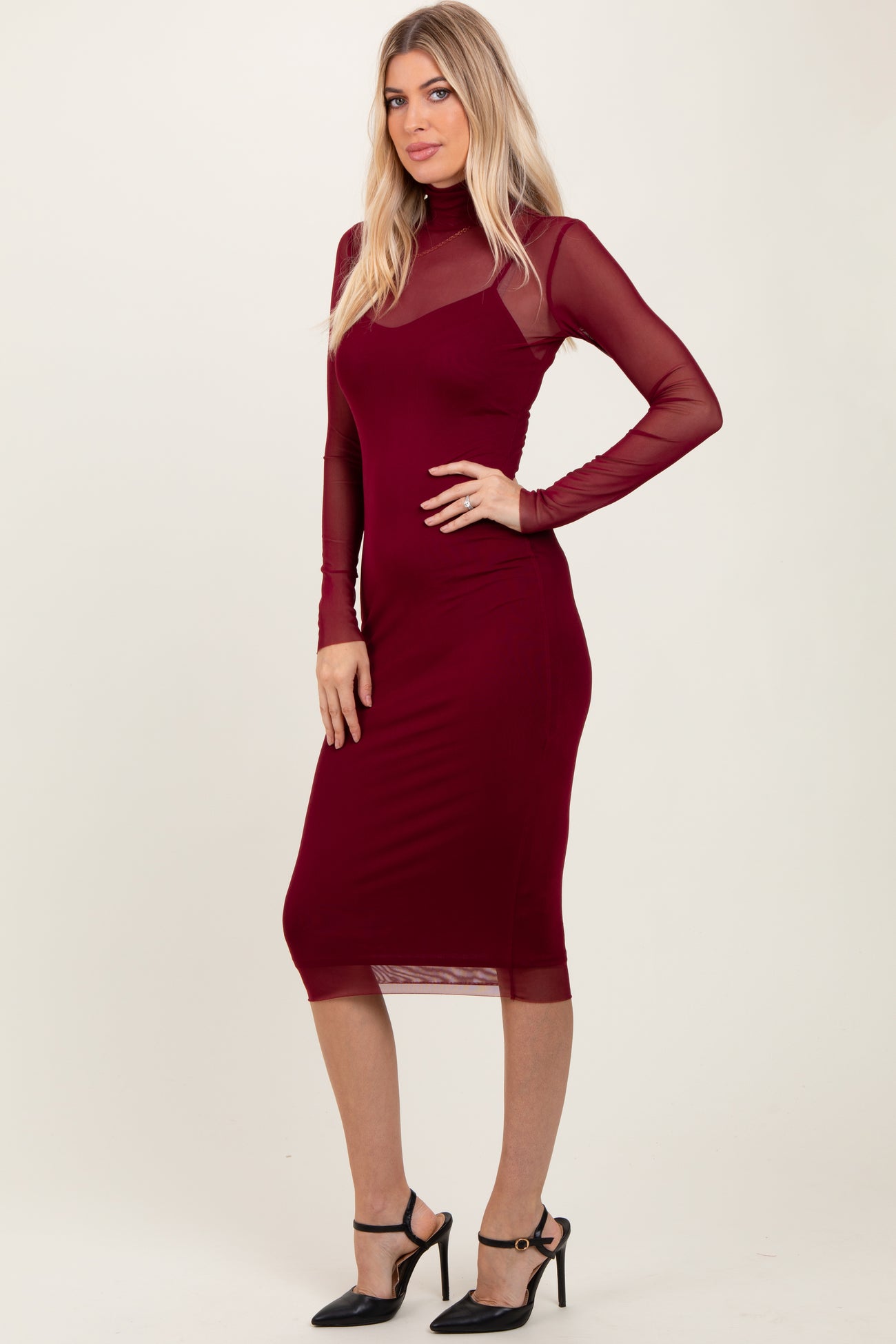 woman wearing a burgundy long sleeve dress with sheer mesh details and a fitted silhouette
