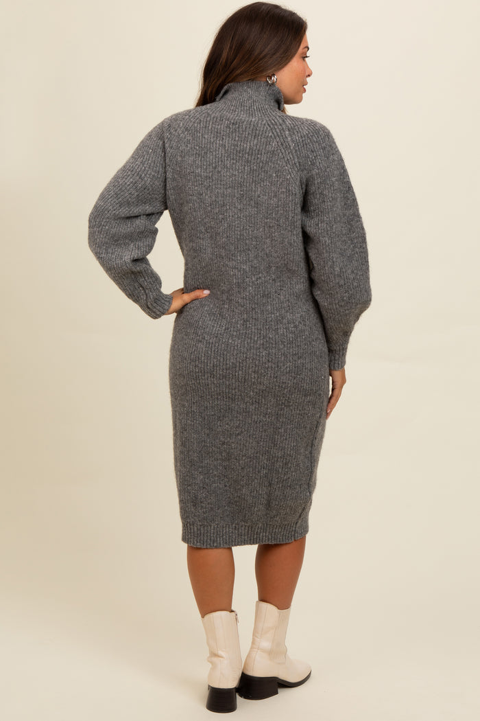woman wearing a gray knitted maternity dress with a high collar and balloon sleeves, styled with ankle boots
