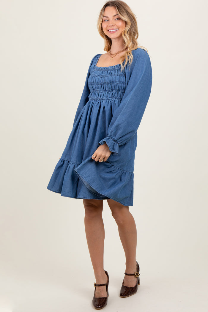 woman wearing a denim blue smocked dress with balloon sleeves and a ruffled hem
