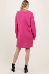 woman wearing a bright pink oversized knitted sweater dress with long sleeves and a relaxed fit, viewed from the back