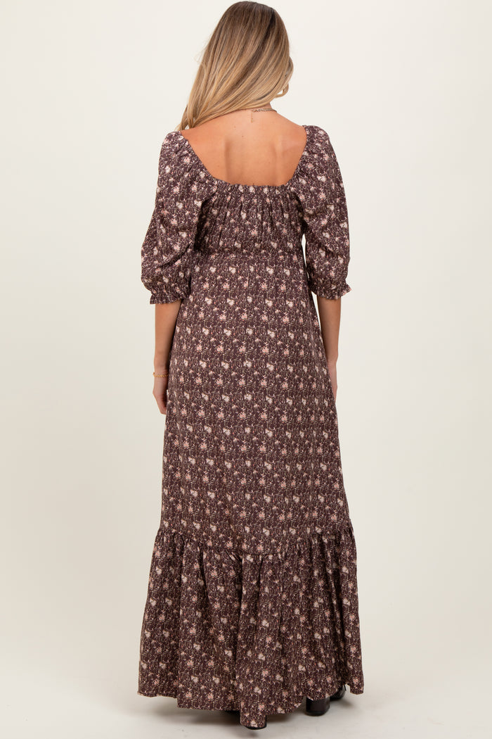 woman wearing a brown floral maternity maxi dress with puff sleeves and a tiered ruffled hem, showing her back