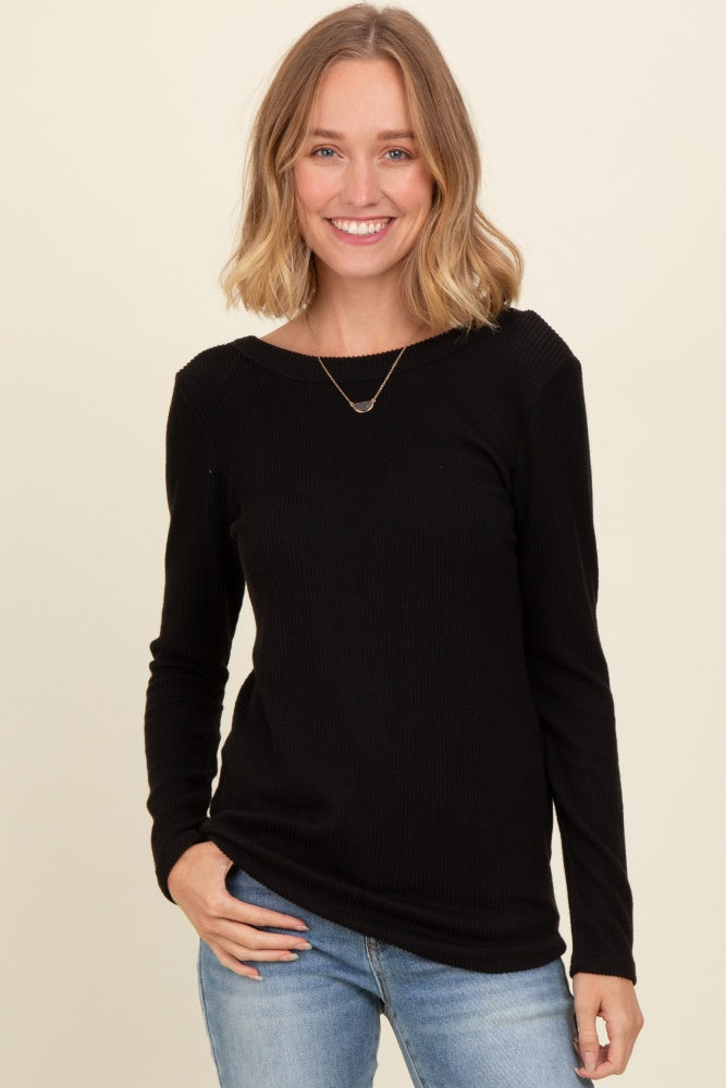 woman wearing a black ribbed long sleeve top and blue jeans, smiling at the camera