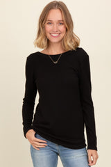 woman wearing a black ribbed long sleeve top and blue jeans, smiling at the camera