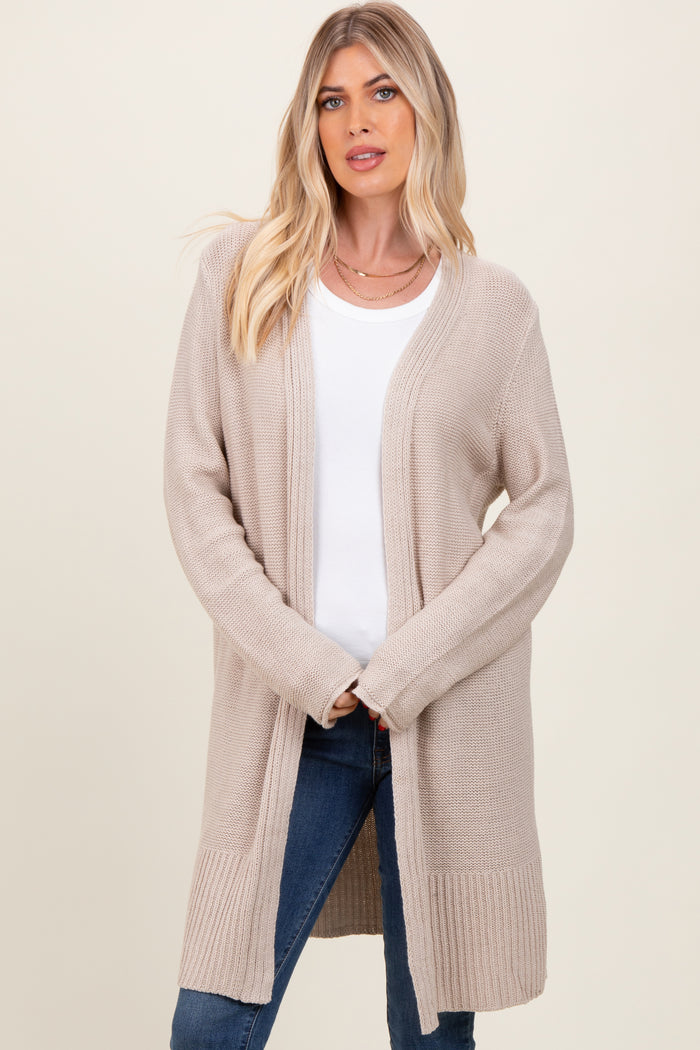 woman wearing a beige long cardigan over a white top and blue jeans