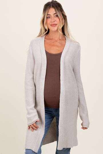 woman wearing a light gray long sleeve maternity cardigan over a brown fitted top and showing her baby bump
