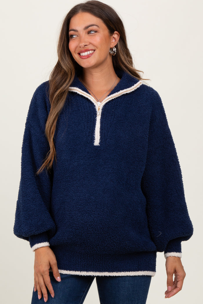 woman wearing a navy blue maternity pullover with a half zip and cream trim, smiling and styled for comfort