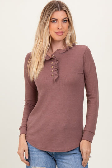 woman wearing a mauve long sleeve henley top with ruffle detail and button placket, styled casually with denim jeans