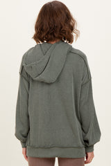 woman wearing a green striped oversized hoodie with a hood and long sleeves, seen from the back