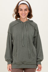 woman wearing an olive green striped oversized hoodie with a front pocket and drawstring hood