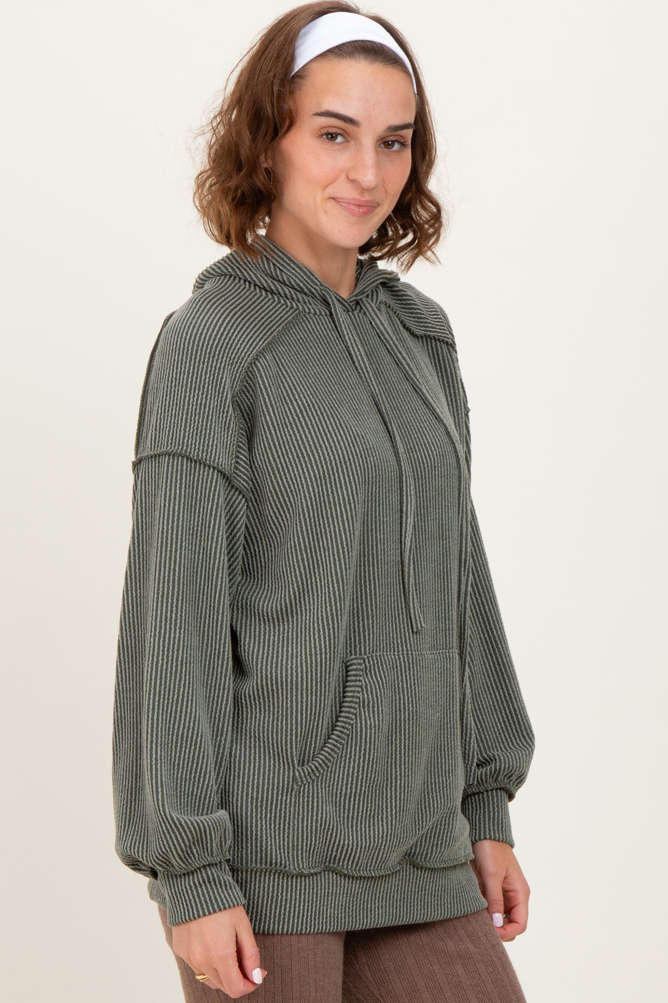 woman wearing a green striped oversized hoodie with a front pocket and drawstring hood