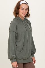 woman wearing a green striped oversized hoodie with a front pocket and drawstring hood