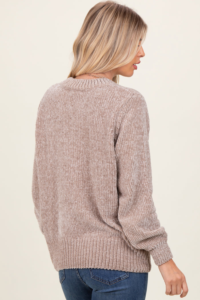 woman wearing a beige long sleeve knit sweater with a textured finish and ribbed hem, shown from the back