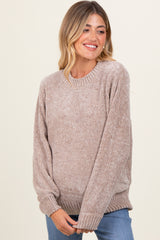 woman wearing a cozy beige maternity sweater with a relaxed fit and ribbed detailing, smiling while holding her baby bump