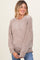 woman wearing a cozy beige maternity sweater with a relaxed fit and ribbed detailing, smiling while holding her baby bump