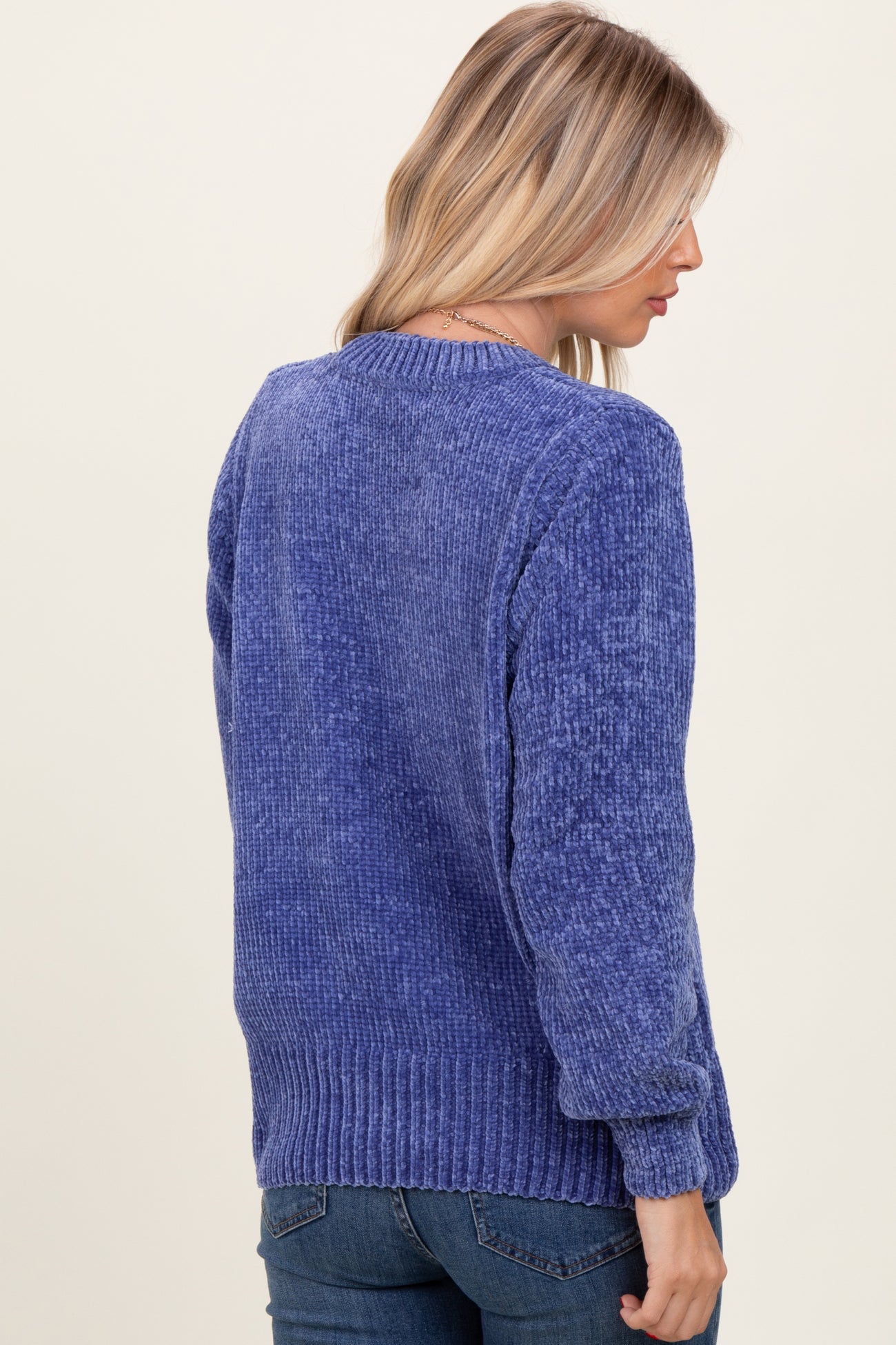 woman wearing a textured purple sweater with a crew neck and ribbed hem, seen from the back