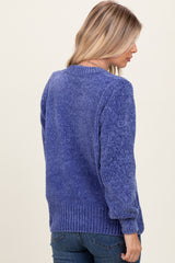 woman wearing a textured purple sweater with a crew neck and ribbed hem, seen from the back