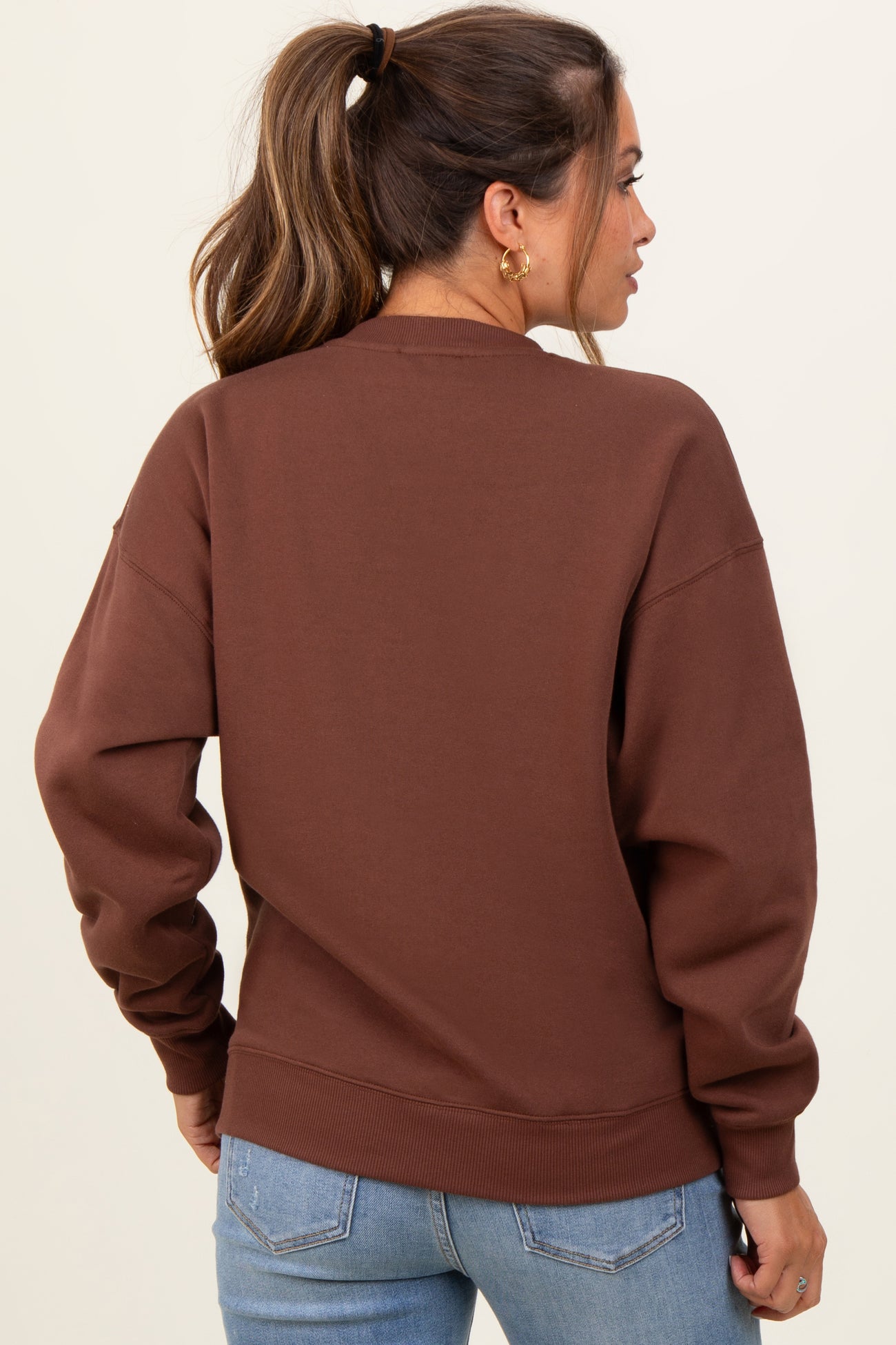 woman wearing a brown maternity sweatshirt, showing the back view with relaxed fit and long sleeves
