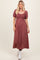 woman wearing a burgundy striped maxi dress with a smocked bodice and puff sleeves, paired with white ankle boots