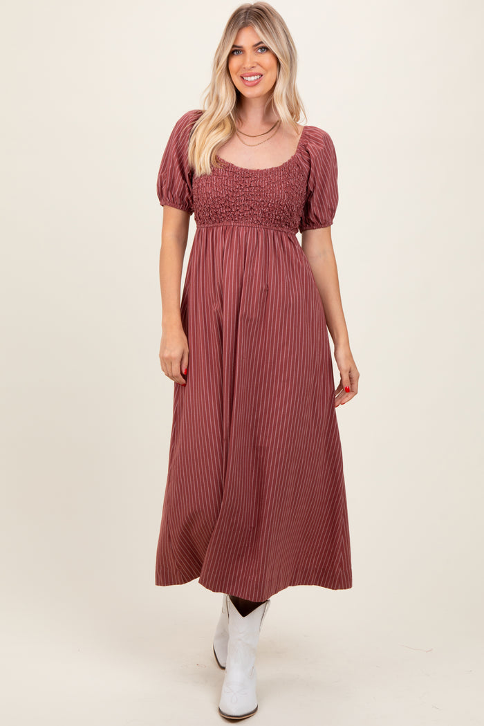 woman wearing a burgundy striped maxi dress with a smocked bodice and puff sleeves, paired with white ankle boots