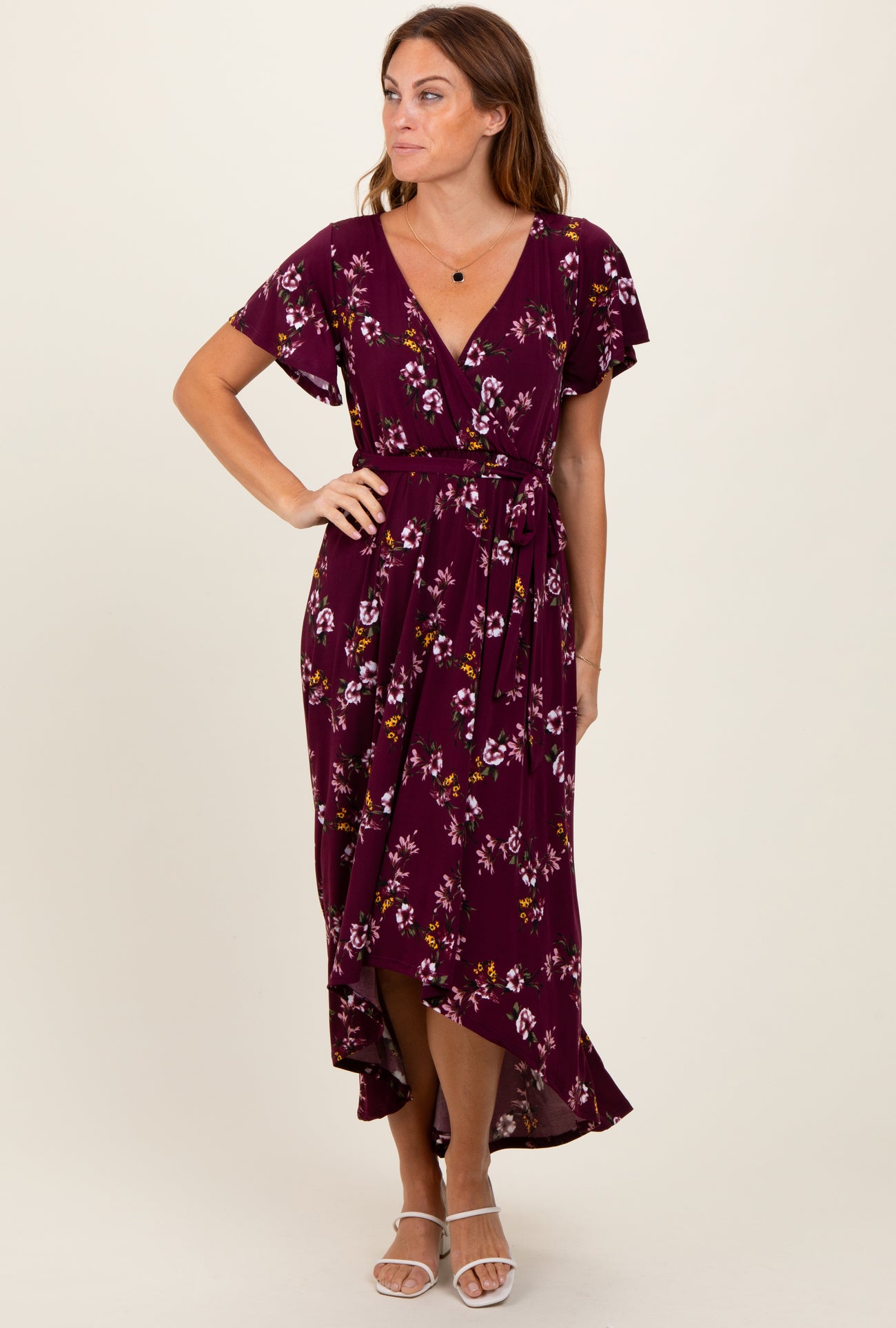 woman wearing a burgundy floral wrap dress with short sleeves and a high-low hemline