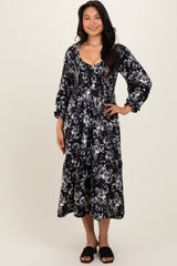 woman wearing a black and white floral midi dress with puffed sleeves and a tiered skirt