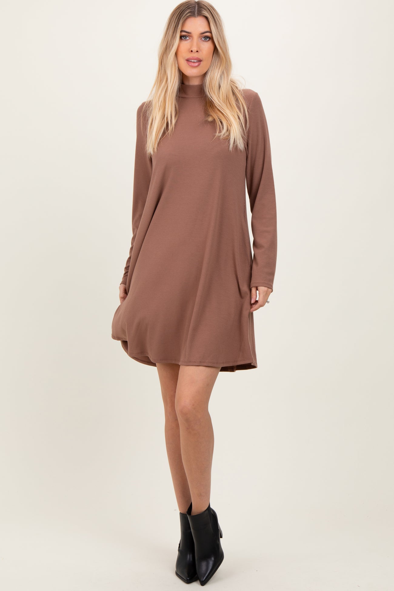 woman wearing a brown long sleeve flared dress with a round neckline and a relaxed fit, paired with black ankle boots
