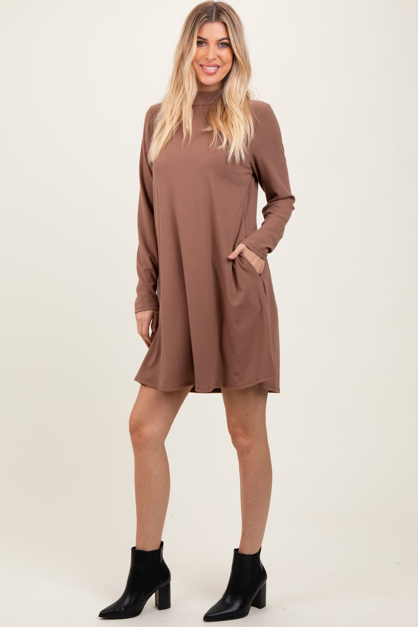 woman wearing a brown long sleeve mini dress with pockets and black ankle boots