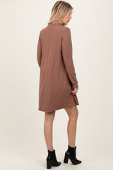 woman wearing a brown long sleeve ribbed dress with a high neckline and side slits, viewed from the back