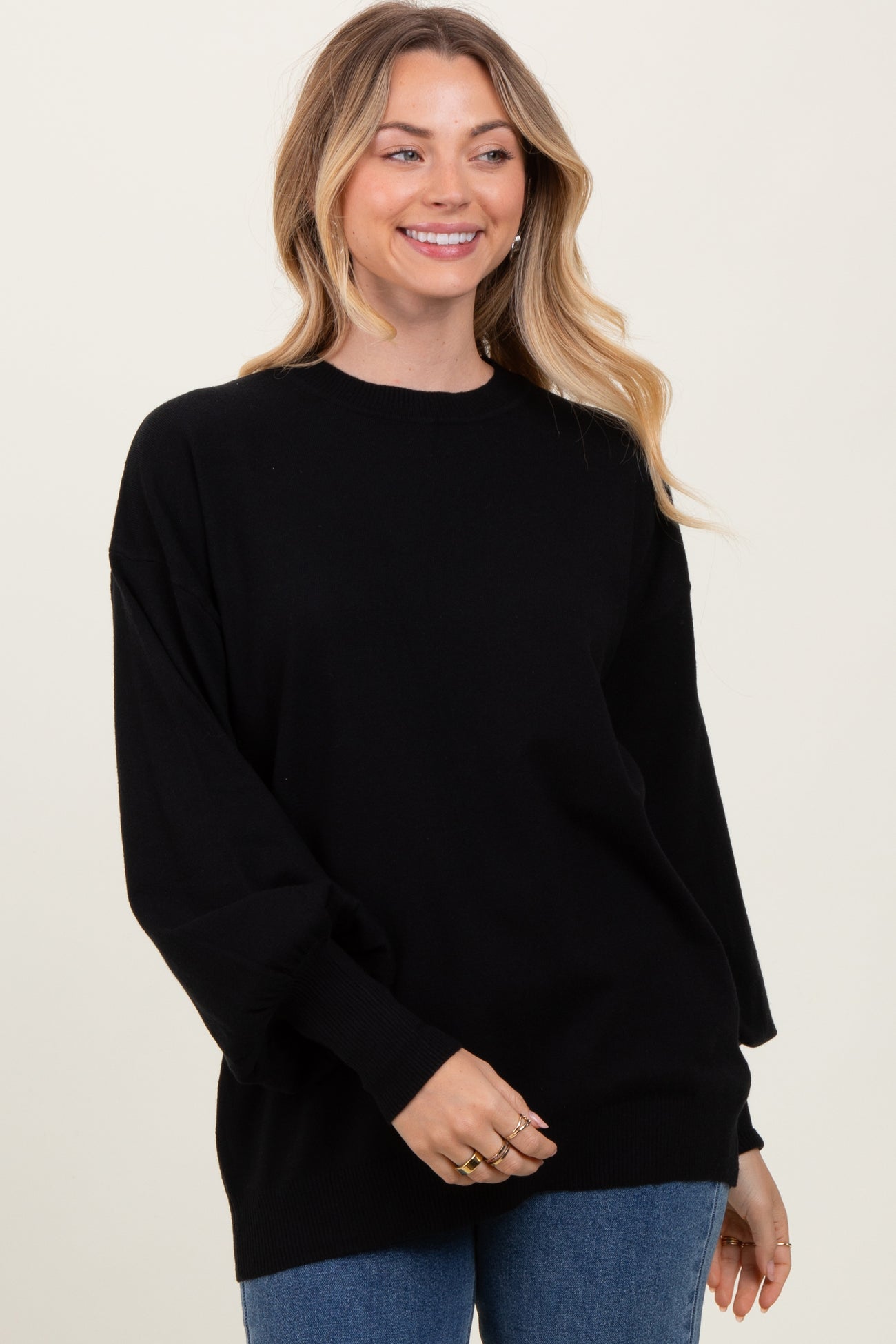 woman wearing a relaxed fit black oversized sweater with long sleeves and a round neckline, smiling