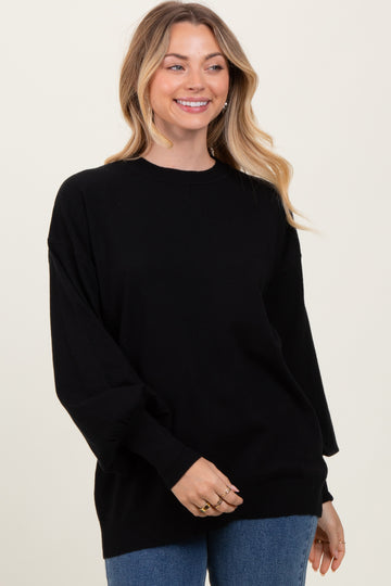 woman wearing a relaxed fit black oversized sweater with long sleeves and a round neckline, smiling