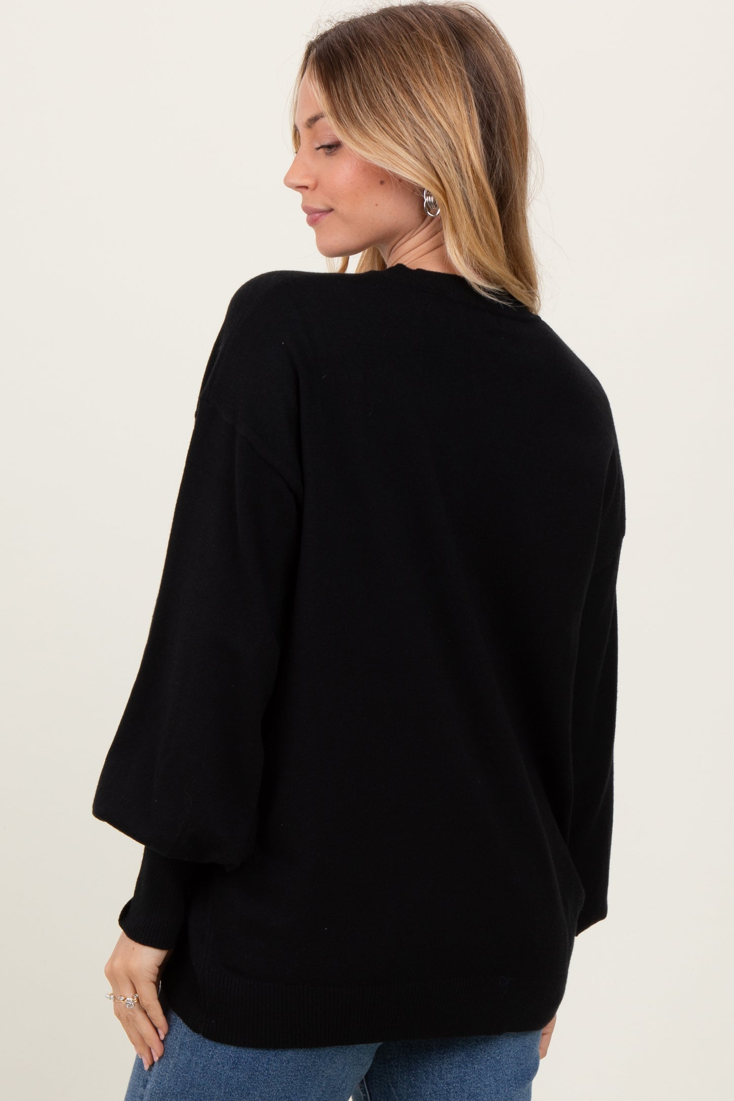 woman wearing a black oversized sweater with balloon sleeves, shown from the back