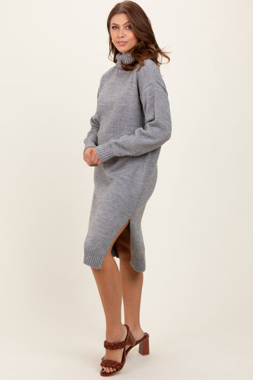 woman wearing a gray long sleeve turtleneck sweater dress with side slits and brown heeled sandals