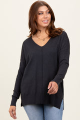 woman wearing a dark gray v-neck oversized sweater with side slits and long sleeves, styled with denim jeans