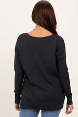 woman wearing a dark gray long sleeve sweater with a relaxed fit and open back, paired with light blue jeans