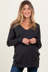 woman wearing a dark gray v-neck maternity sweater with a visible baby bump and smiling
