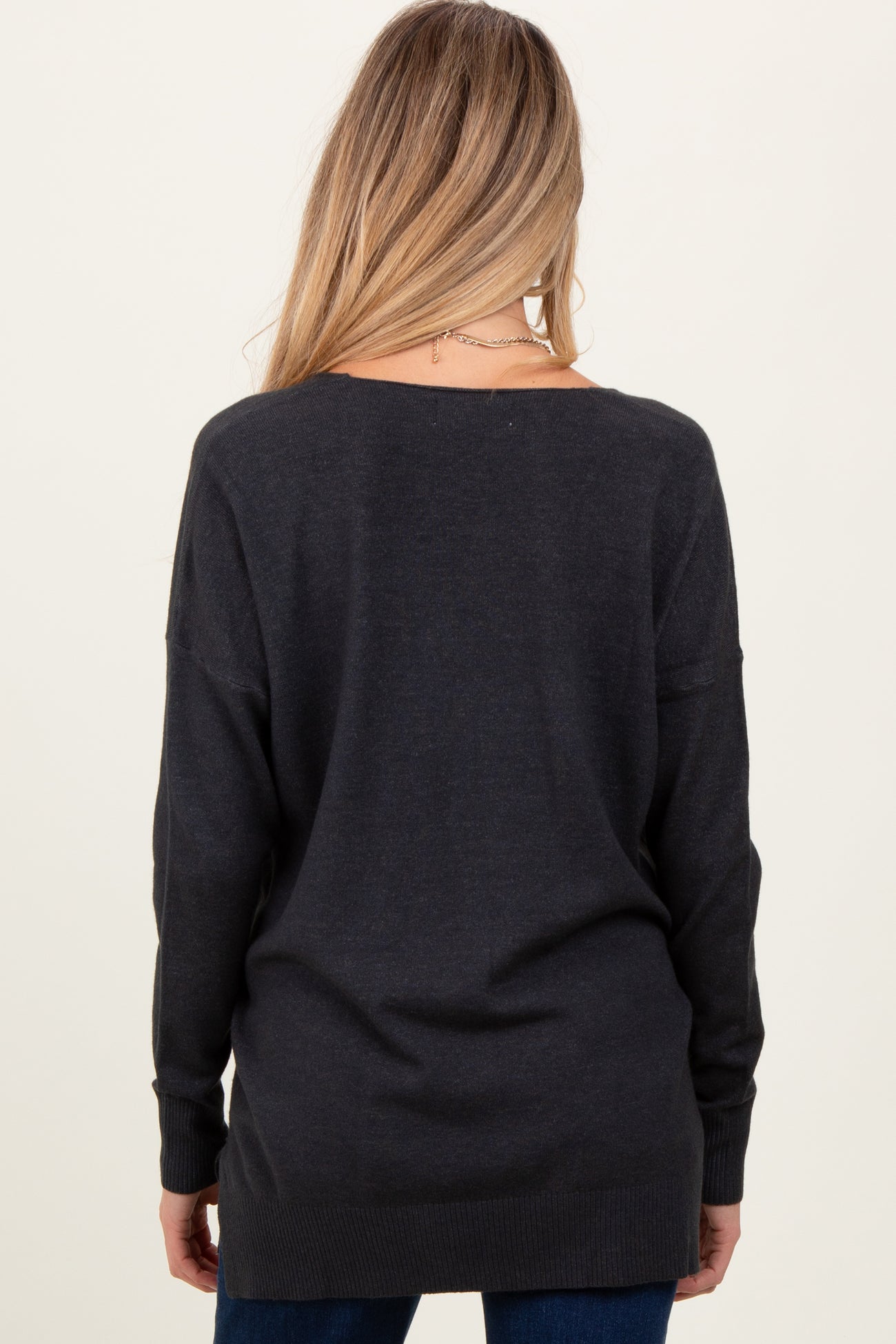 woman wearing a dark gray oversized maternity sweater from the back, featuring long sleeves and a relaxed fit