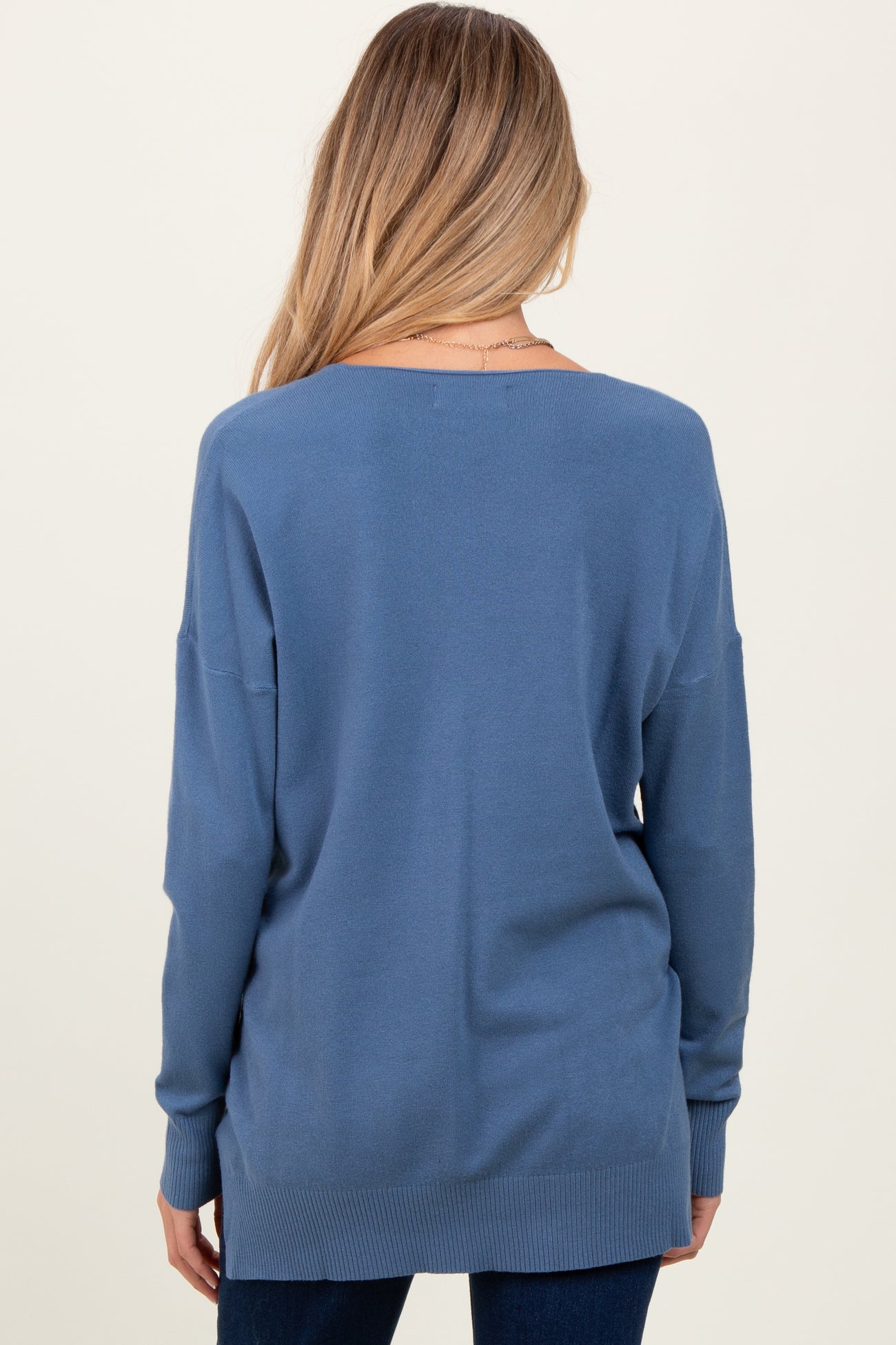 woman wearing a relaxed fit blue maternity sweater from the back with long sleeves and a dropped shoulder design