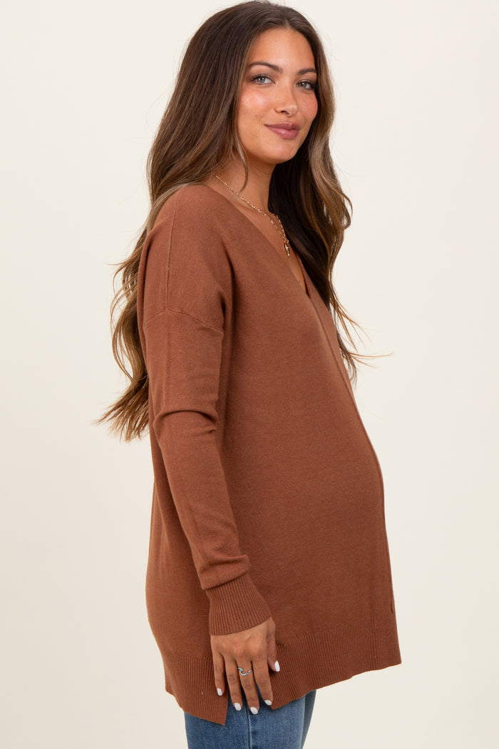 woman wearing a rust v-neck maternity sweater and showing her baby bump