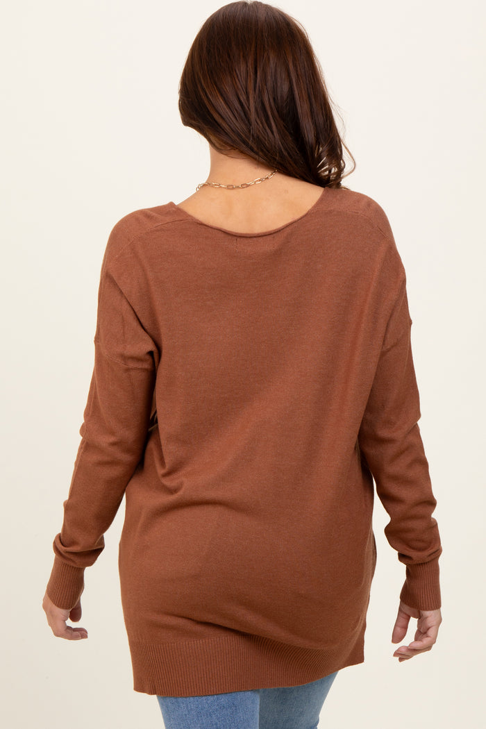 woman wearing a brown oversized sweater with a low back and long sleeves, styled with blue jeans