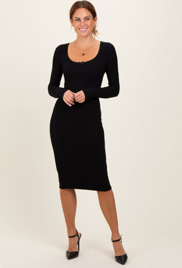 woman wearing a black long sleeve ribbed midi dress with a scoop neckline and fitted silhouette