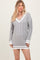 woman wearing a gray cable-knit mini sweater dress with white trim and a deep v-neckline