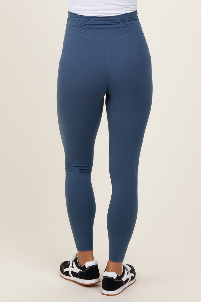 woman wearing blue maternity leggings, shown from the back with a high waistband and a fitted style