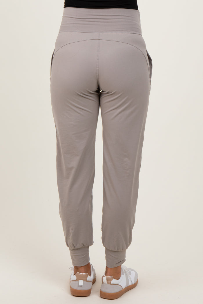 woman wearing light gray maternity joggers with elastic waistband and side pockets, view from the back